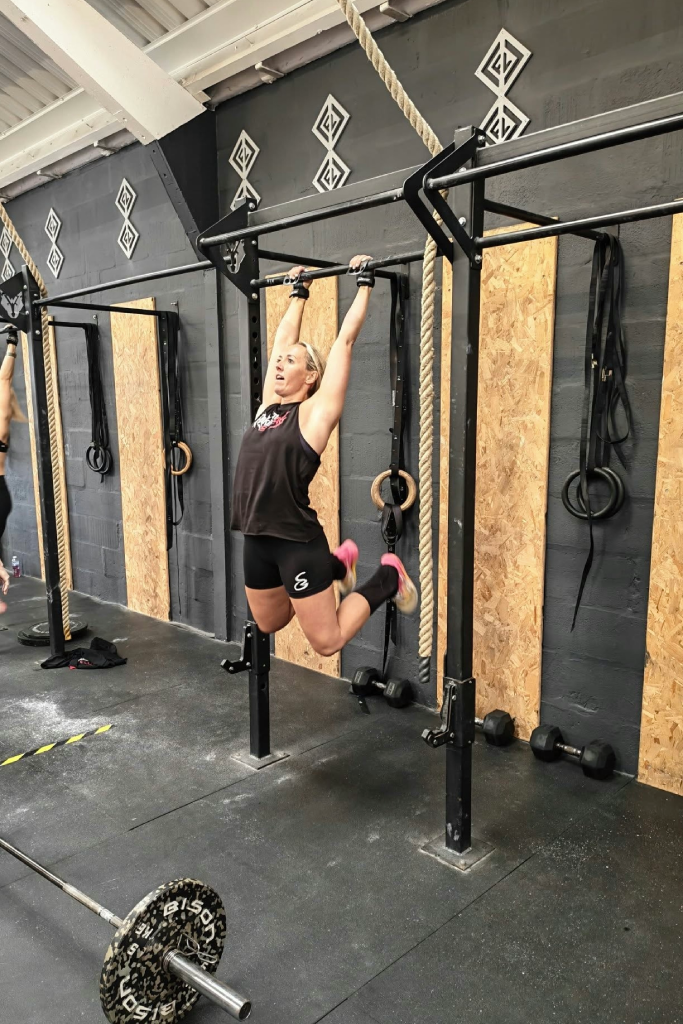 Woman executing dynamic pull-up in gym.